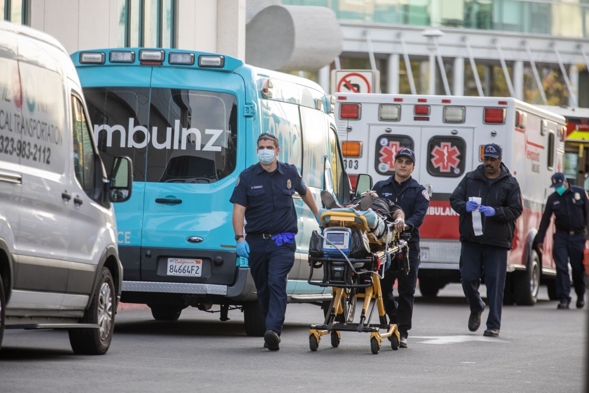 EMT poussant une civière à côté d'ambulances garées