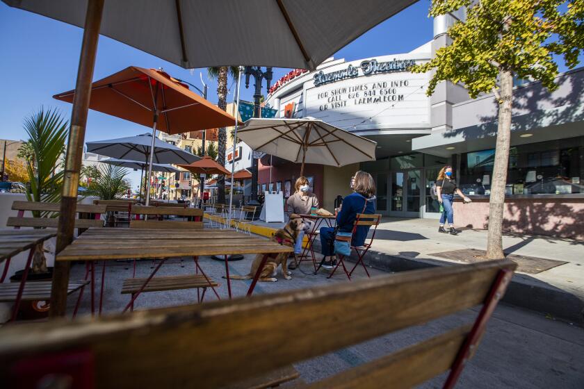 PASADENA, CA - NOVEMBER 22: People dine with their dog in front of the closed Laemmle Theatre on Colorado Blvd. where several businesses have closed and many struggle to stay open during California state-mandated coronavirus closures, restrictions and curfews Sunday, Nov. 22, 2020 in Pasadena, CA. (Allen J. Schaben / Los Angeles Times)