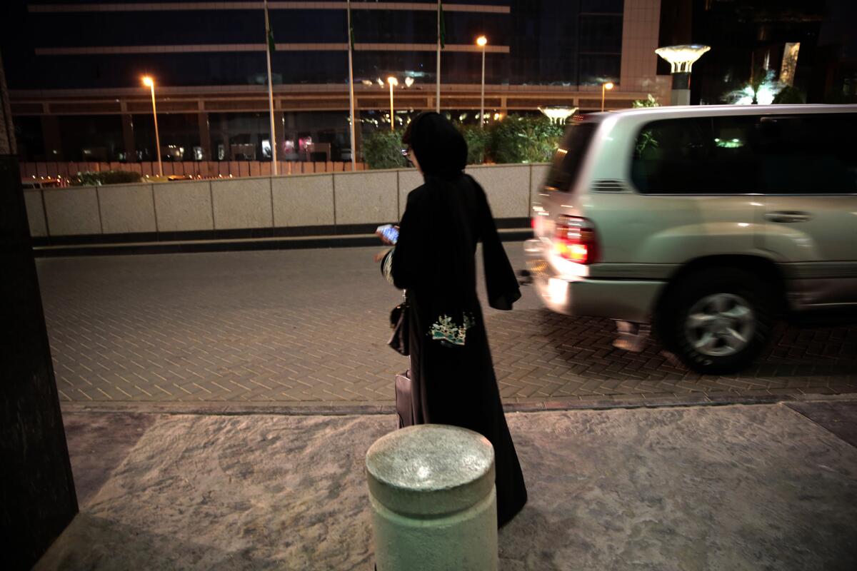 A woman waits for an Uber car at a shopping mall in Riyadh, Saudi Arabia. Since women are not allowed to drive in the conservative kingdom, they must hire cars or rely on a male relative to ferry them around.