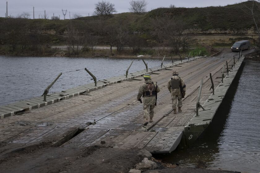 Ukrainian servicemen walk on a pontoon bridge across the Inhulets river in Kherson region, Ukraine, Saturday, Dec. 3, 2022. (AP Photo/Evgeniy Maloletka)