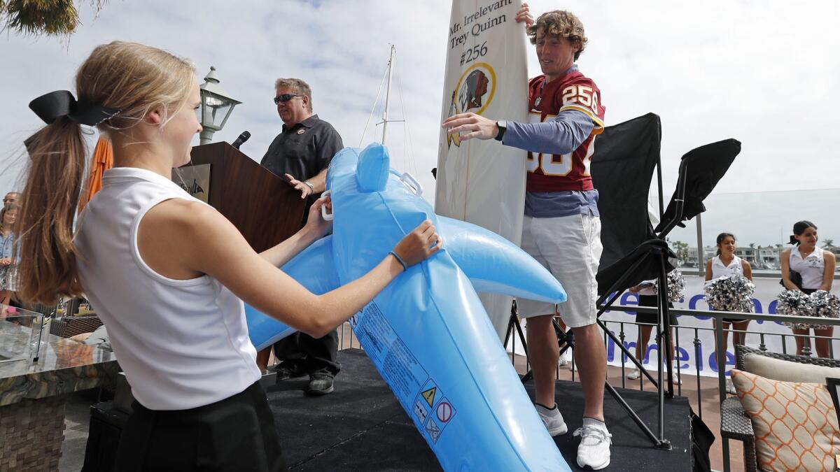 Mr. Irrelevant XLIII, Trey Quinn, right, accepts a surfboard and inflatable shark, gifted by Wayne Smith, top left, of Corona del Mar Properties during the "Welcome to Newport" festivities at the Balboa Bay Resort on Saturday, June 16.
