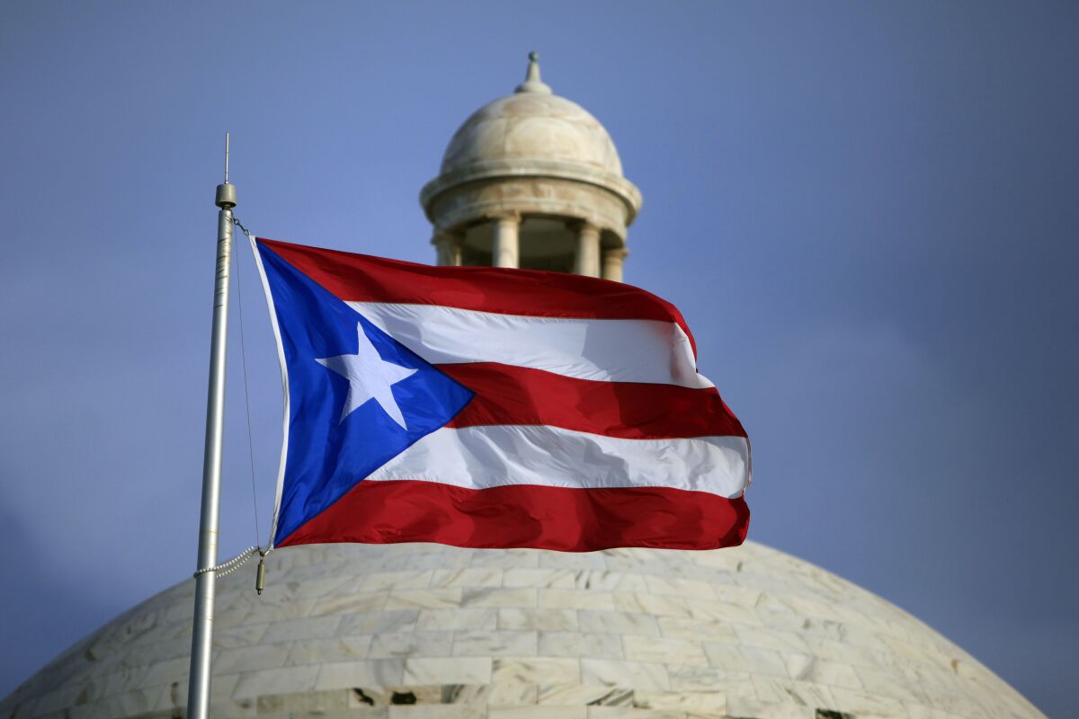 FILE - In this July 29, 2015 file photo, the Puerto Rican flag flies in front of Puerto Rico's Capitol as in San Juan, Puerto Rico. Puerto Rico’s government formally exited bankruptcy Tuesday, March 14, 2022, completing the largest public debt restructuring in U.S. history after announcing nearly seven years ago that it was unable to pay its more than $70 billion debt. (AP Photo/Ricardo Arduengo, File)