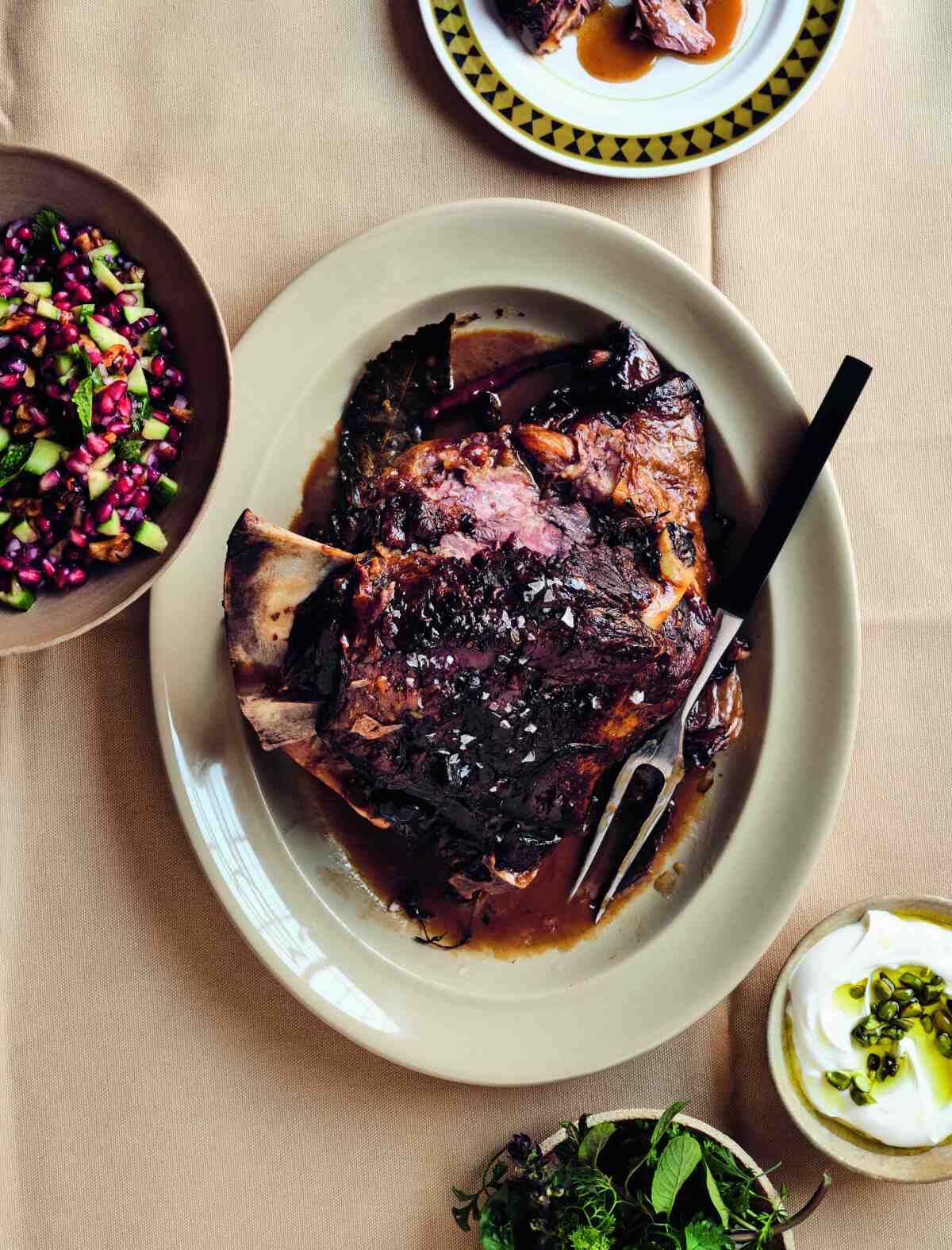 Crushed orange and rosemary braised lamb on an oval platter with a serving fork