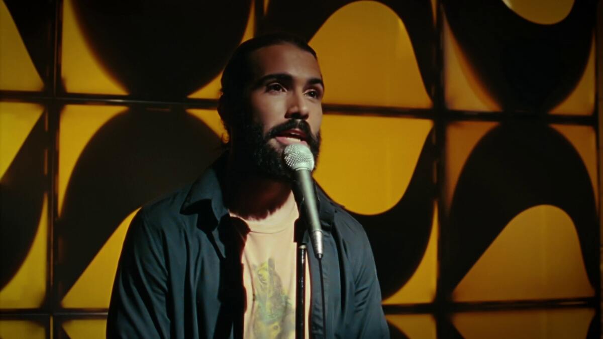 Gonzalo Trigueros standing at a microphone in "Such a Funny Life."