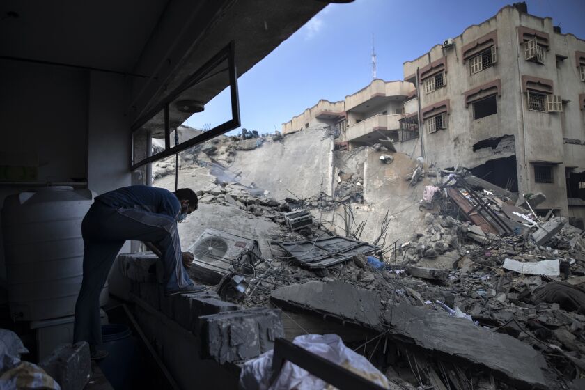 A Palestinian man inspects the damage of a six-story building which was destroyed by an early morning Israeli airstrike, in Gaza City, Tuesday, May 18, 2021. Israel carried out a wave of airstrikes on what it said were militant targets in Gaza, leveling a six-story building in downtown Gaza City, and Palestinian militants fired dozens of rockets into Israel early Tuesday, the latest in the fourth war between the two sides, now in its second week. (AP Photo/Khalil Hamra)