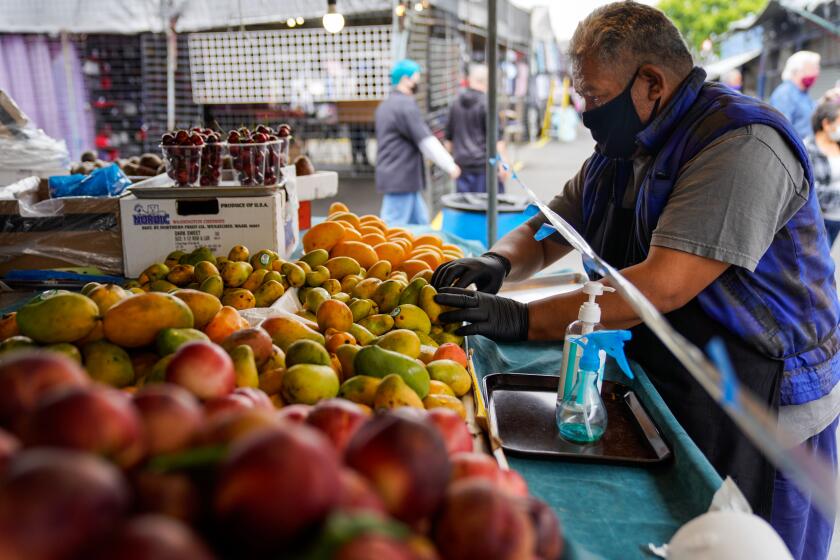 SANTA FE SPRINGS, CA - JUNE 20: Claudio Eclicerio, 51, organizes fruits at his stand at the Santa Fe Springs Swap Meet on Saturday, June 20, 2020 in Santa Fe Springs, CA. Swap Meets across the Southland are struggling to bounce back after finally re-opening amid the ongoing Coronavirus pandemic. (Kent Nishimura / Los Angeles Times)