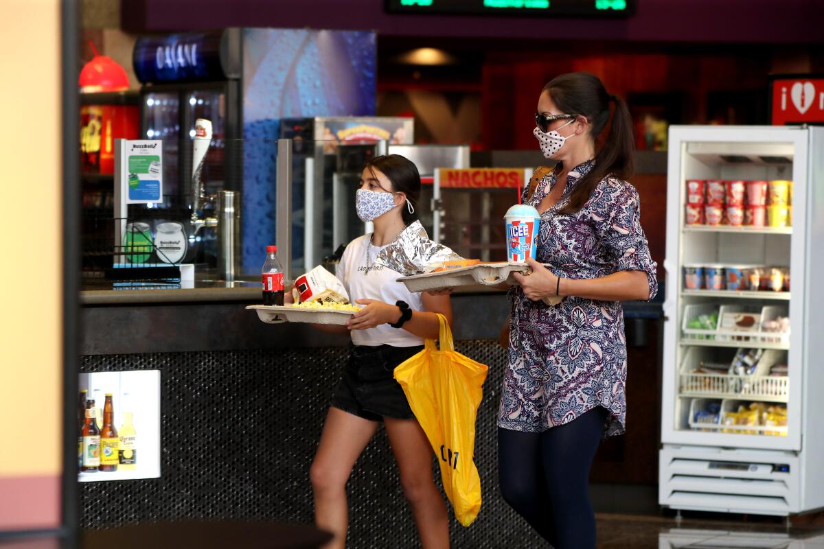Moviegoers wearing masks grab snacks at the just reopened Cinemark Century Cinema in Huntington Beach on Friday.