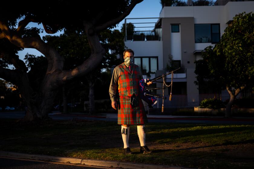 SANTA MONICA, CA - MAY 01: Andrew McGregor poses at the corner of San Vicente Blvd and Ocean Avenue, on his way to Palisades Park to perform "Amazing Grace" on his bagpipes at sunset, in Santa Monica, CA, Friday, May 1, 2020, during the coronavirus pandemic. Playing the bagpipes for about two years, McGregor has been performing at sunset since around mid-March, with a small number of people gathering nearby to watch and listen. (Jay L. Clendenin / Los Angeles Times)