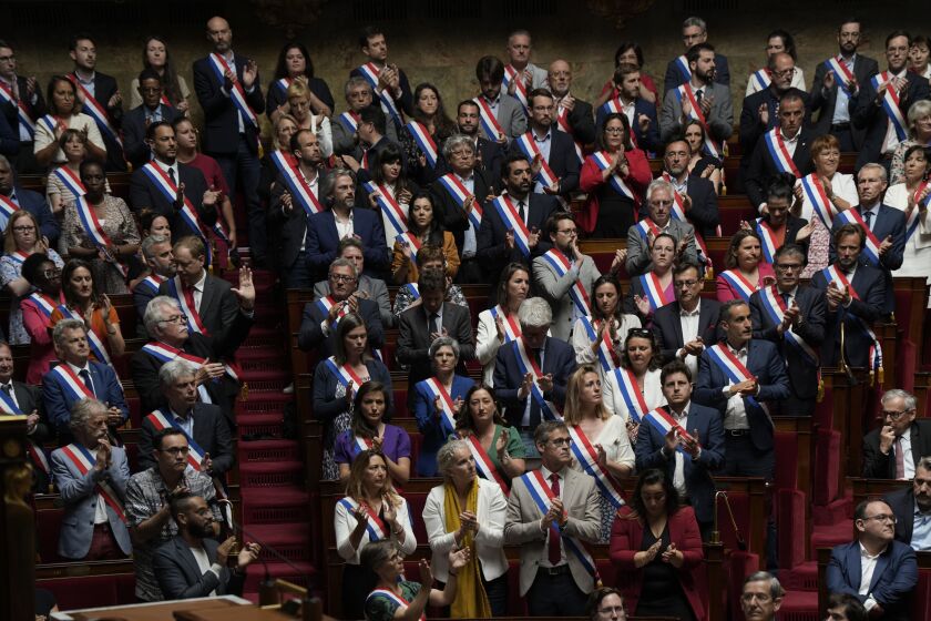 Miembros de la Asamblea Nacional de Francia se ponen en pie y aplauden en homenaje a niños víctimas de un ataque en una localidad de los Alpes franceses, el jueves 8 de junio de 2023. (AP Foto/Lewis Joly)