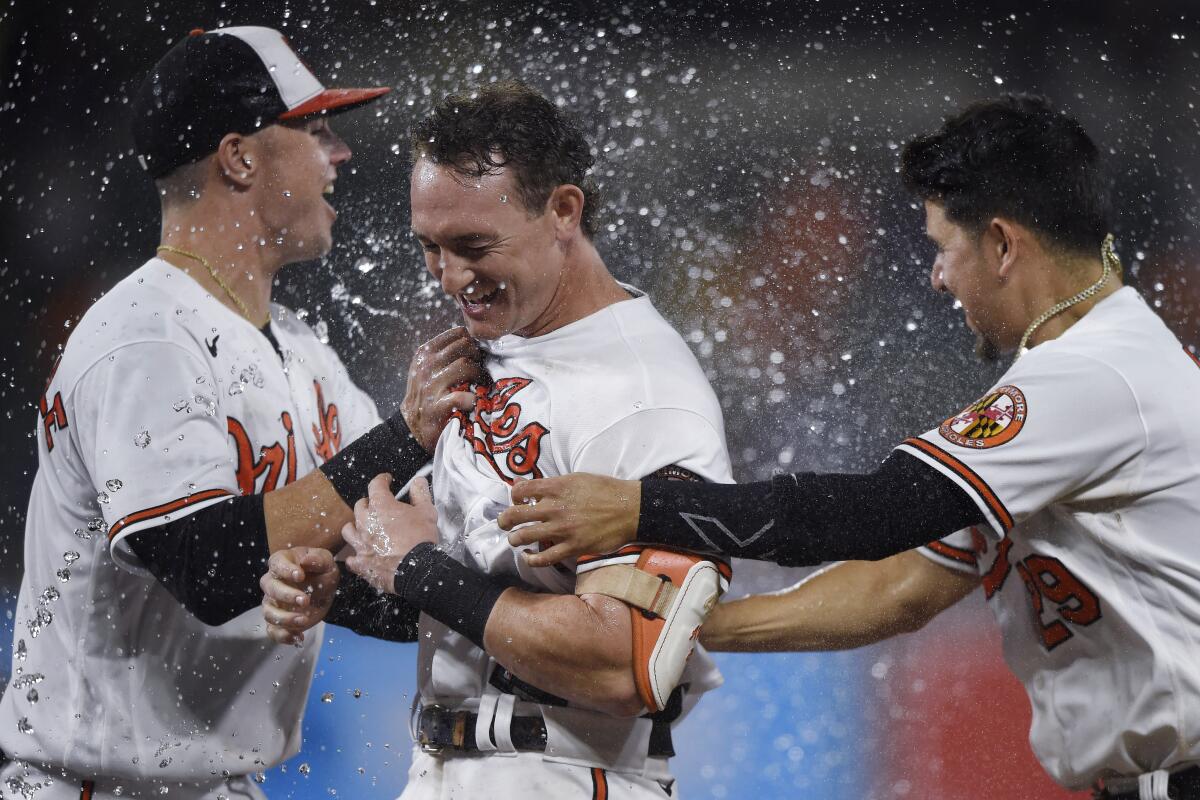Baltimore Orioles' Austin Hays, center, is congratulated by Ryan Mountcaste, left, and Ramon Urias after driving in the winning run against the New York Yankees during the 10th inning of a baseball game Thursday, Sept. 16, 2021, in Baltimore. The Orioles won 3-2. (AP Photo/Gail Burton)