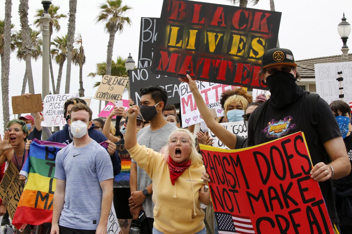 Protesters hold signs during a Black Lives Matter rally at Pier Plaza, with counter protesters across the street, on June 20.