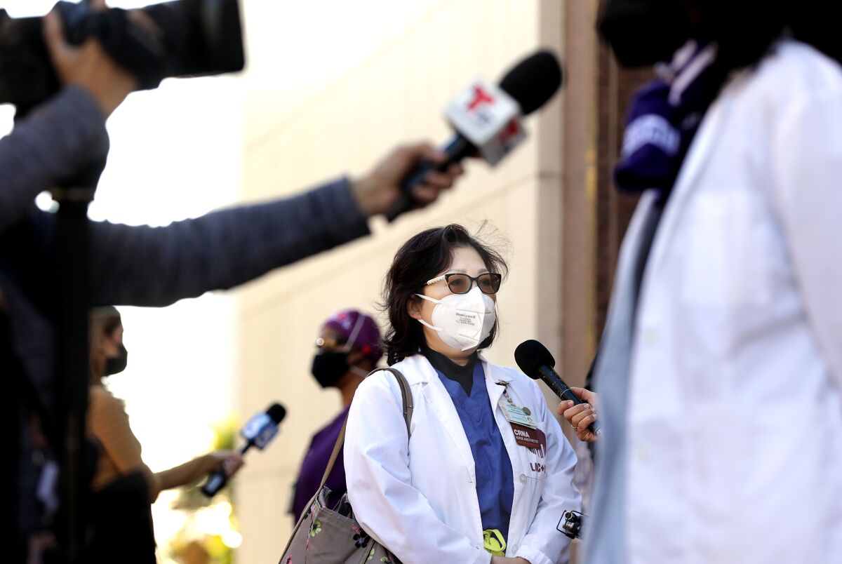 Nurse anesthetist Kelly Zhou, center, gives interviews after a news conference in Los Angeles.