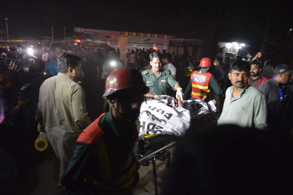 Pakistani rescuers use a stretcher to shift a body from a bomb blast site in Lahore. (Arif Ali / AFP/Getty Images)