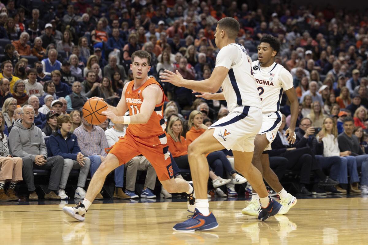 Syracuse's Joseph Girard III (11) drives with the ball against Virginia players during the first half of an NCAA college basketball game in Charlottesville, Va., Saturday, Jan. 7, 2023. (AP Photo/Mike Kropf)
