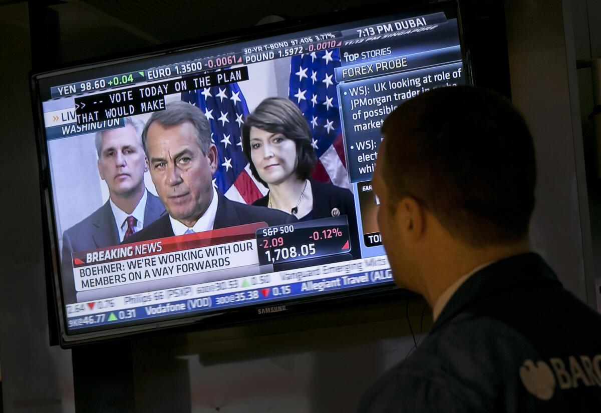 Specialist Frank Masiello watches a television monitor on the floor of the New York Stock Exchange showing a Washington news conference by House Speaker John Boehner.