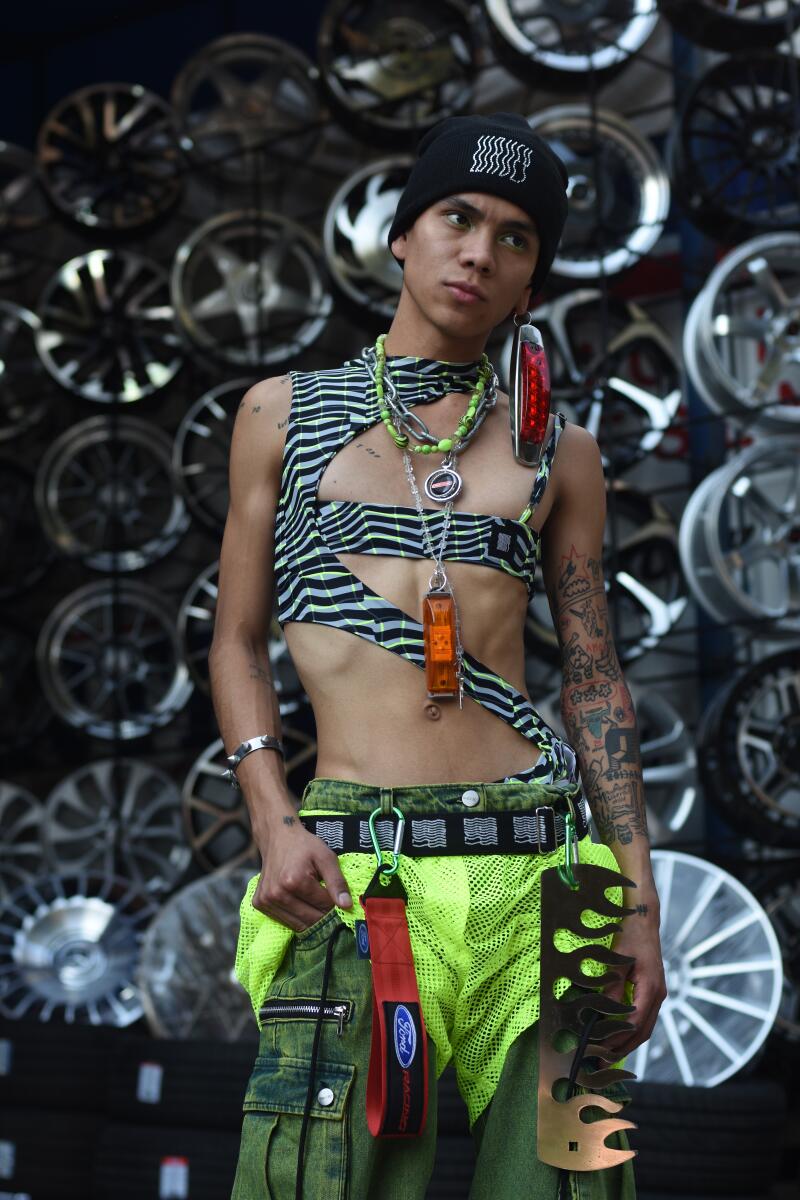 Israel wears Wavey zig-zag top, beanie, acid cargo pants, chrome fanny pack, Planeta neon mesh shorts, Tuzza custom earring.