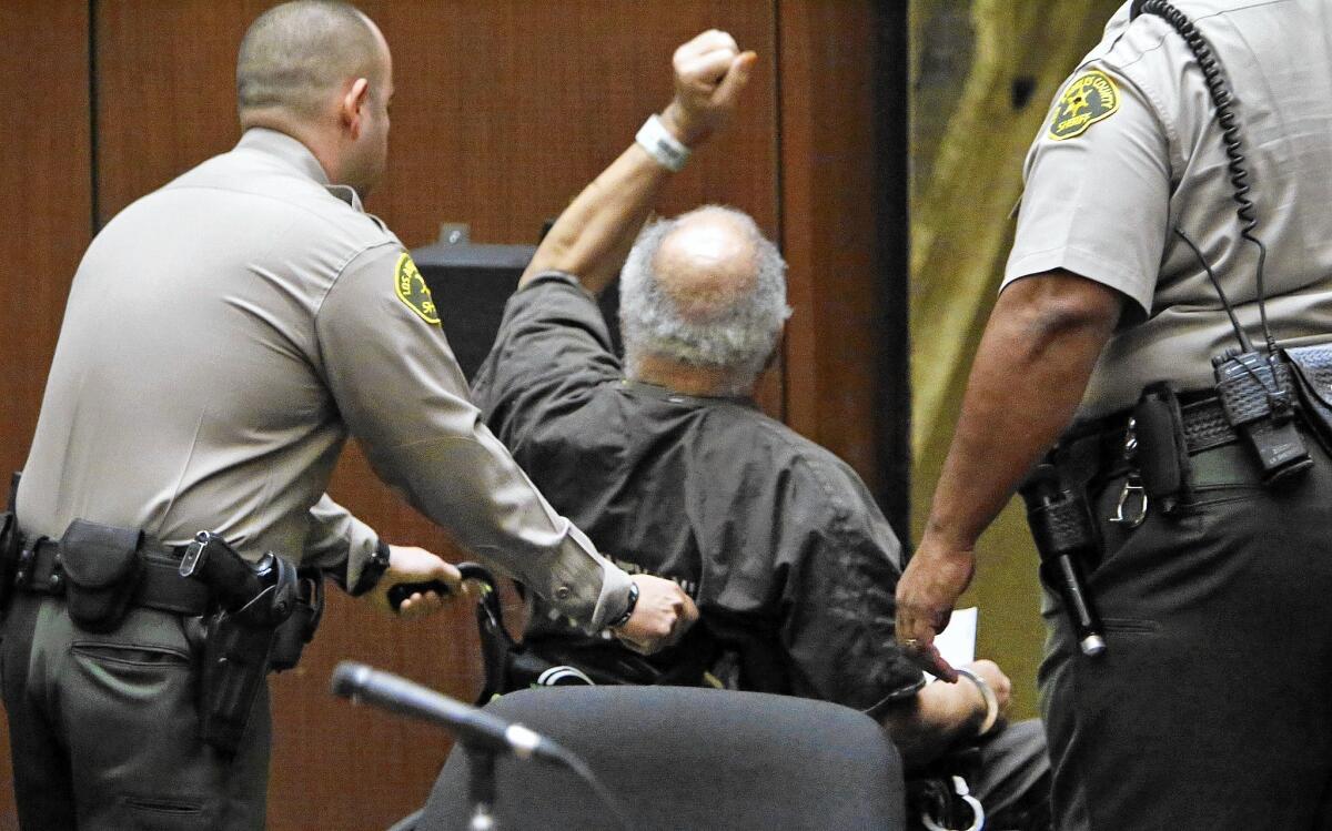 Samuel Little, 74, raises his arm in defiance as he is taken out of the courtroom amid applause after his sentencing for killing three women in South L.A. in the 1980s.