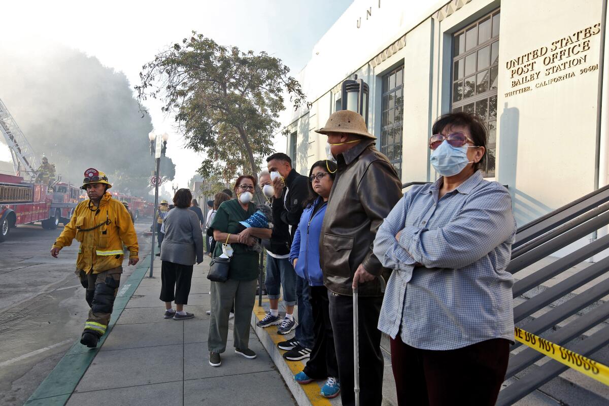 People wait across the street Thursday as firefighters pour water on the church in Whittier about four hours after the fire was first reported.