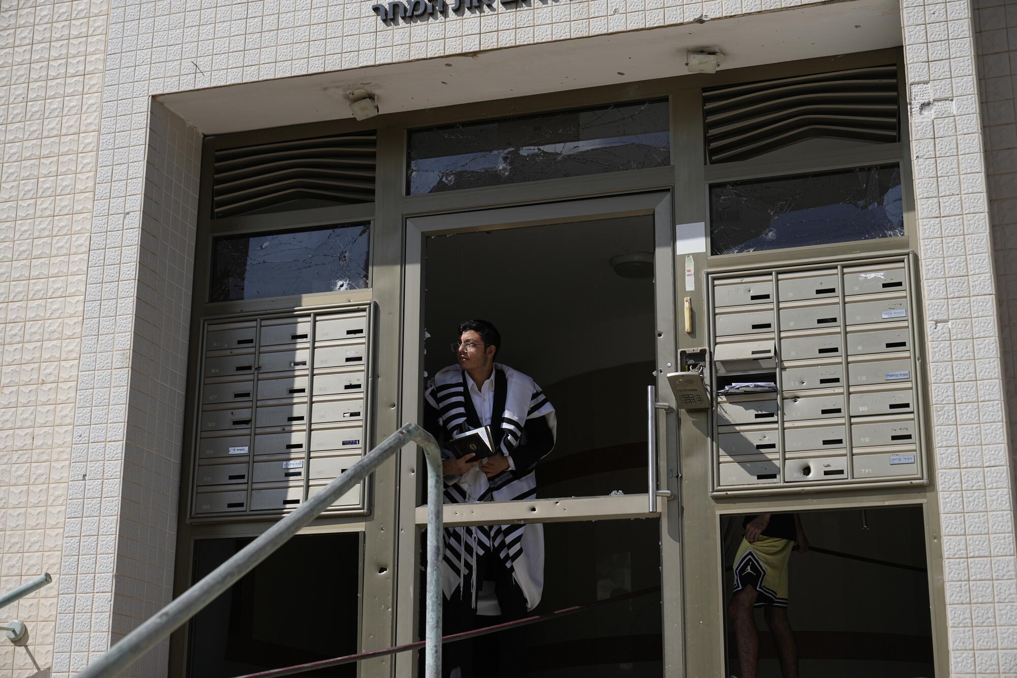 An ultra-Orthodox Jewish man peering out of a building after a rocket attack from the Gaza Strip in Ashkelon, Israel