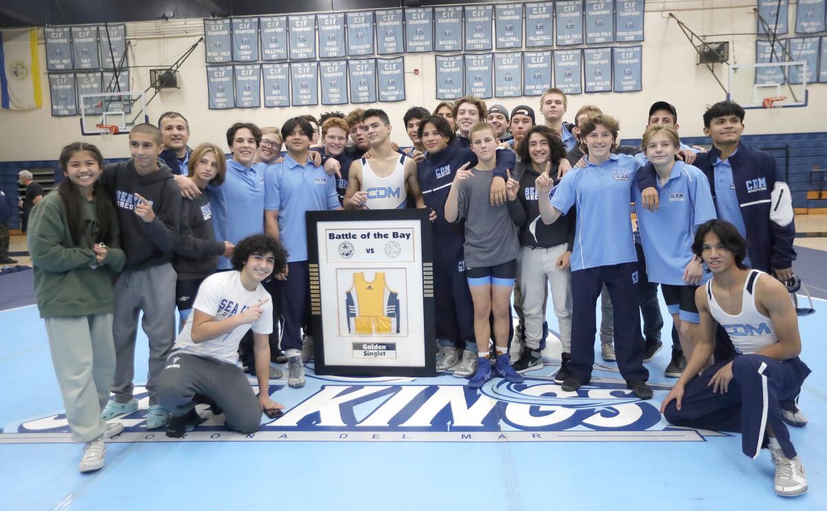 The Corona del Mar wrestling team celebrates with the Golden Singlet trophy, awarded to the winner of the Battle of the Bay.