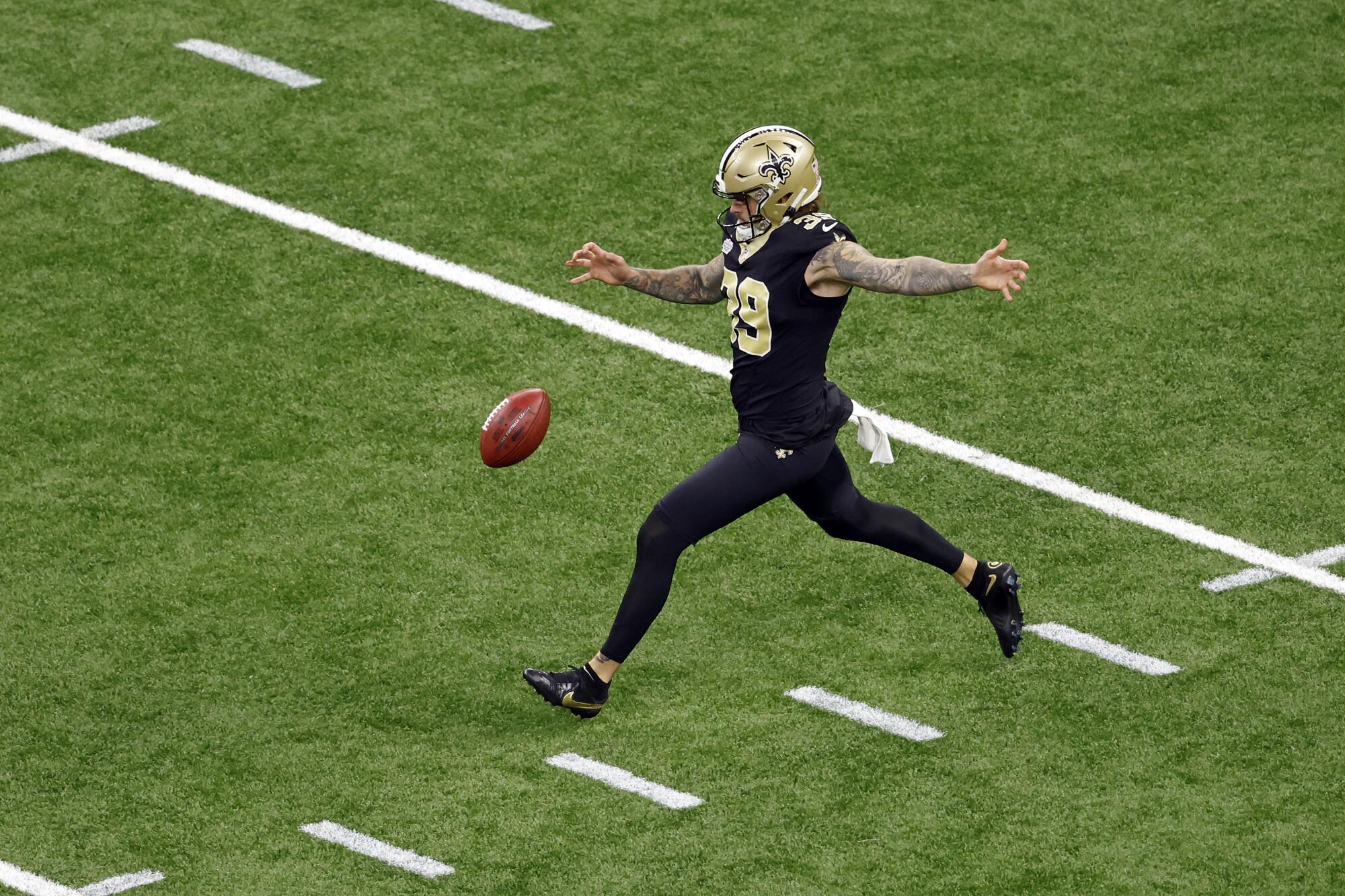 Saints punter Lou Hedley stretches out his arm after dropping the ball in the air and steps forward preparing to kick it