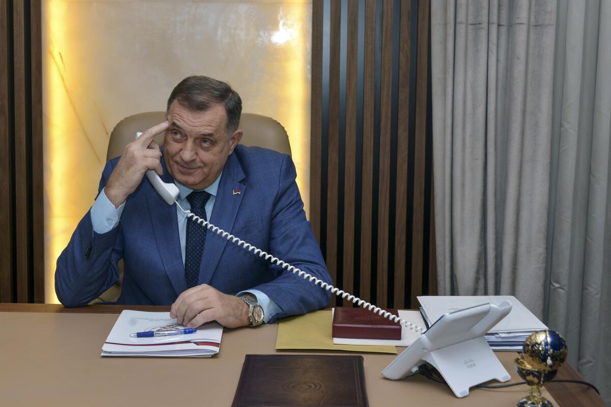 Bosnian Serb leader Milorad Dodik uses his phone at a desk.