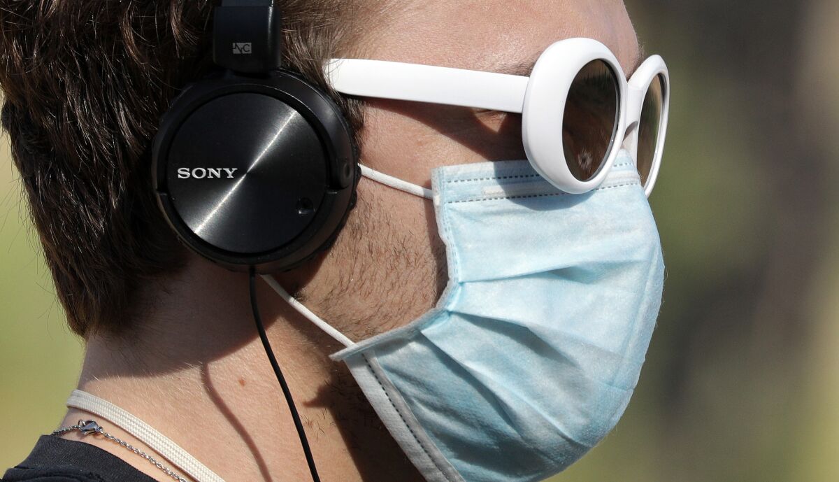 A man wears headphones and a face mask.