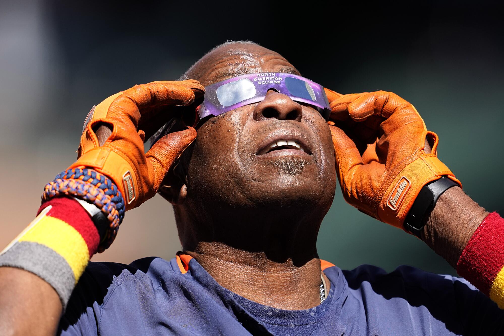 A man uses eclipse glasses while looking up at the sky