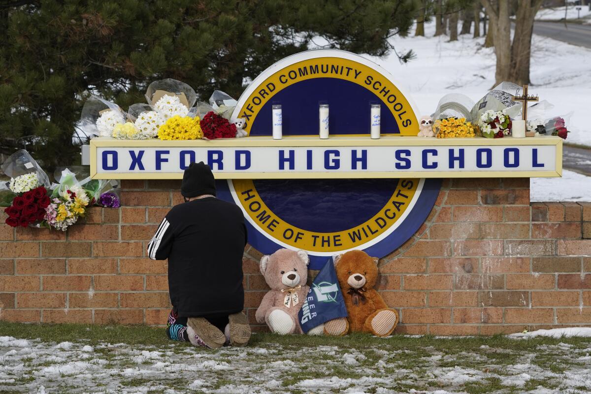 Person kneeling to pray at school shooting memorial site