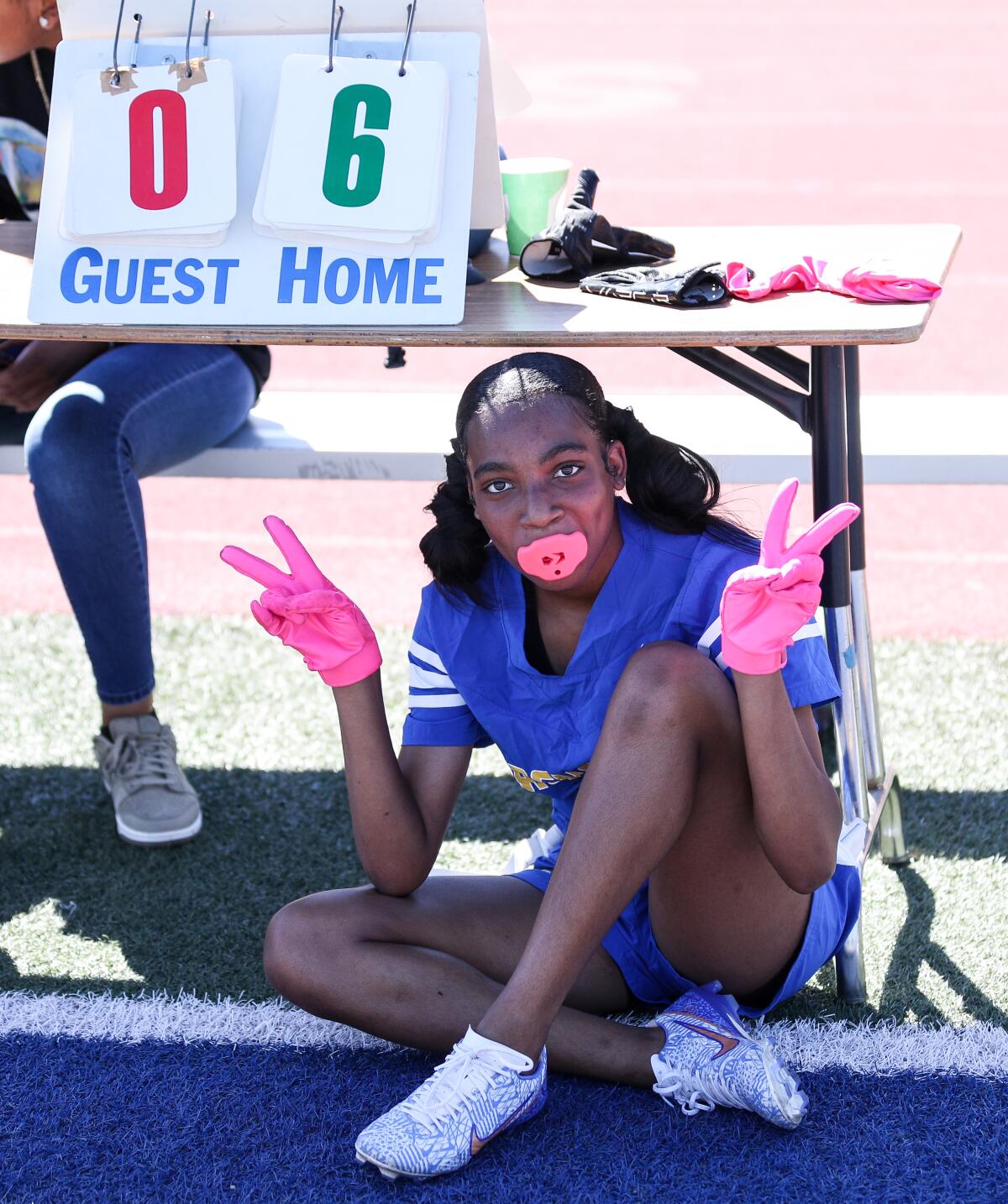 Crenshaw's Cheyenne Hickman finds shade under a desk during a girls' flag football game against Hawkins.