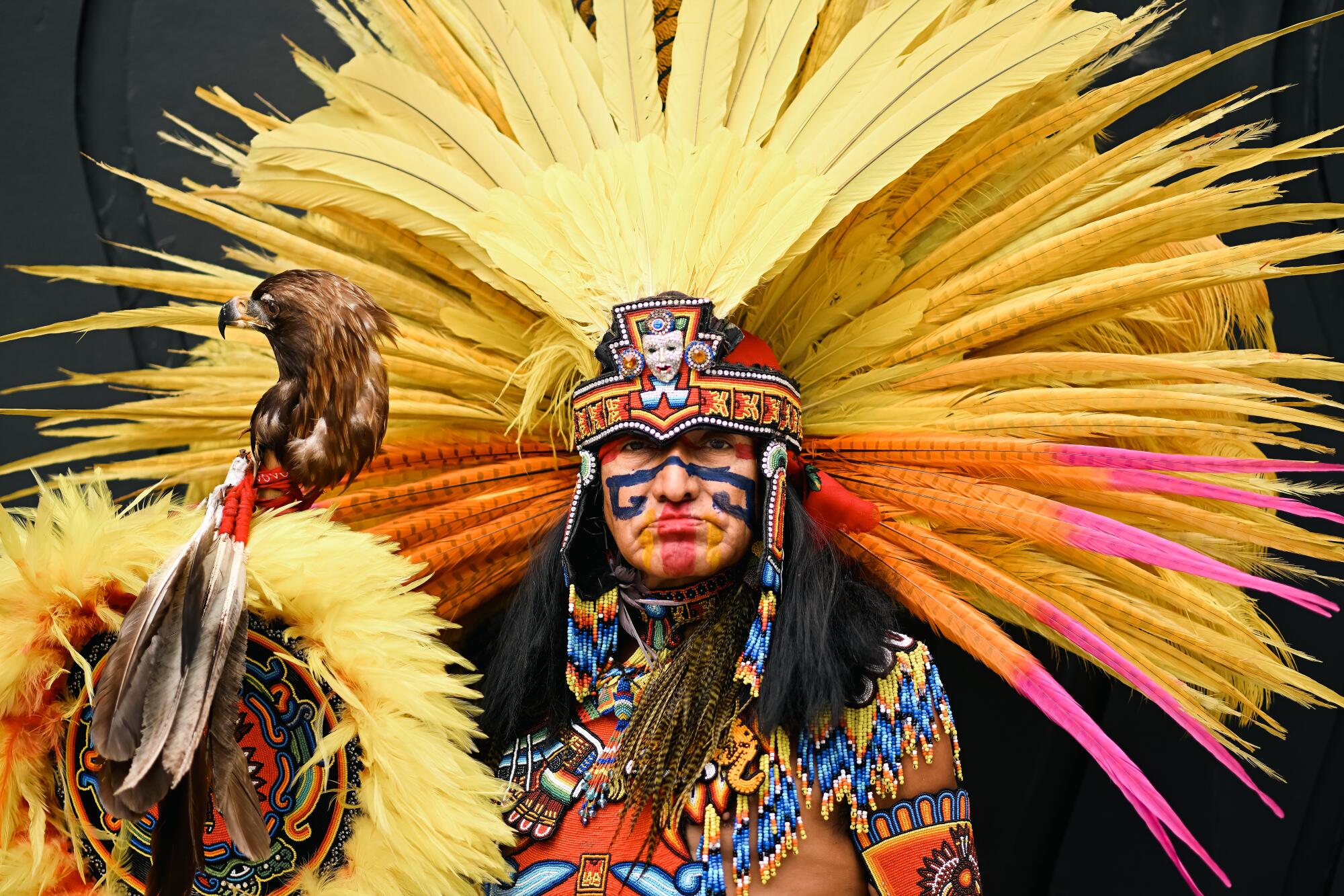 Lazaro Arvizu wears traditional Danza Azteca regalia like face paint, feathers and beading.