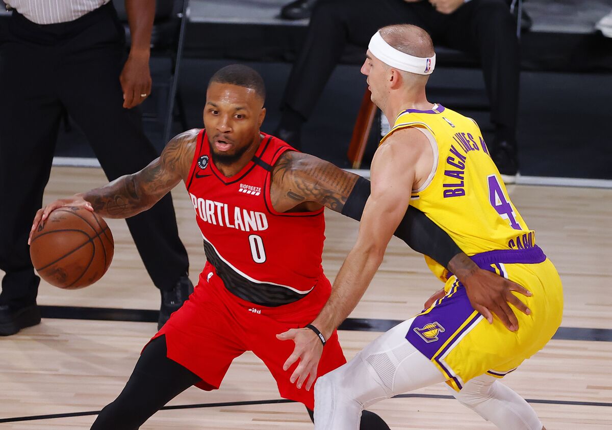 Portland Trail Blazers' Damian Lillard drives the ball against Lakers guard Alex Caruso.