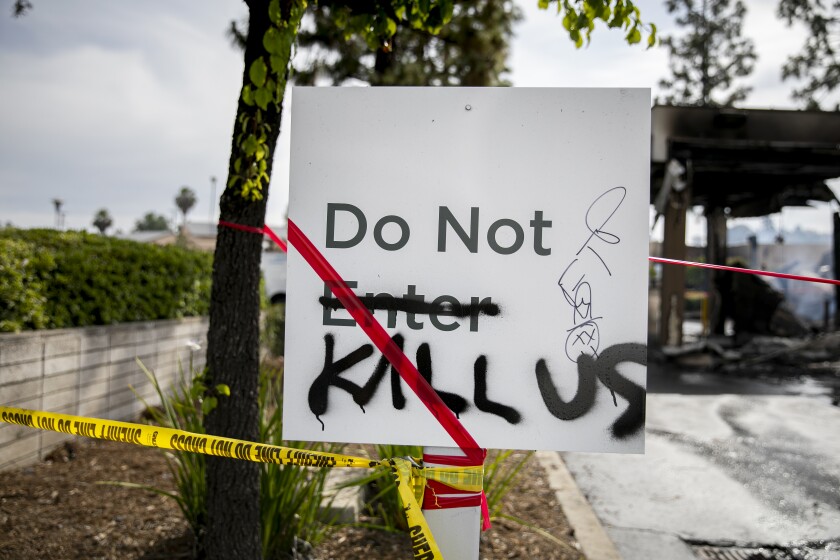 Graffiti is scrawled on a sign outside the burnt out Union Bank building as volunteers help to clean up on May 31, 2020 in La Mesa, California.
