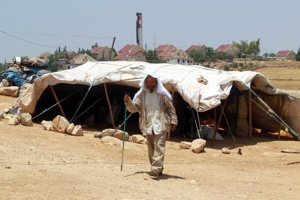 A Palestinian man walks outside his family's home, which consists of tents and shacks, near the Jewish settlement of Karmel in the West Bank.