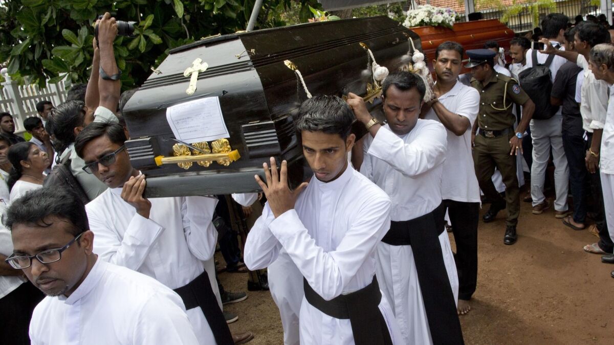 Clerics carry coffins during a funeral service April 23 for the Easter Sunday bomb blast victims at St. Sebastian Church in Negombo, Sri Lanka.