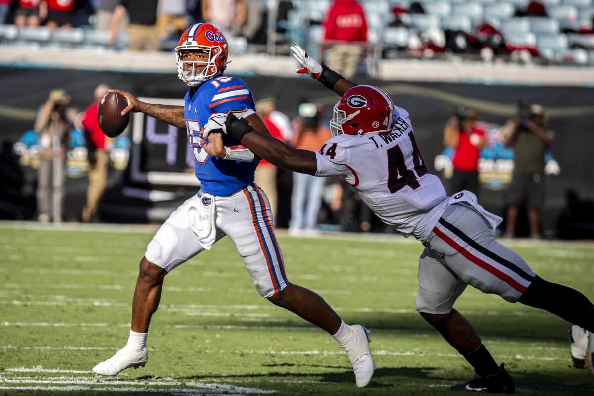 Florida quarterback Anthony Richardson (15) scrabbles out to he pocket while being chased by Georgia defensive lineman Travon Walker (44) during the first half of an NCAA college football game Saturday, Oct. 30, 2021, in Jacksonville, Fla. (Stephen B. Morton/Atlanta Journal-Constitution via AP)