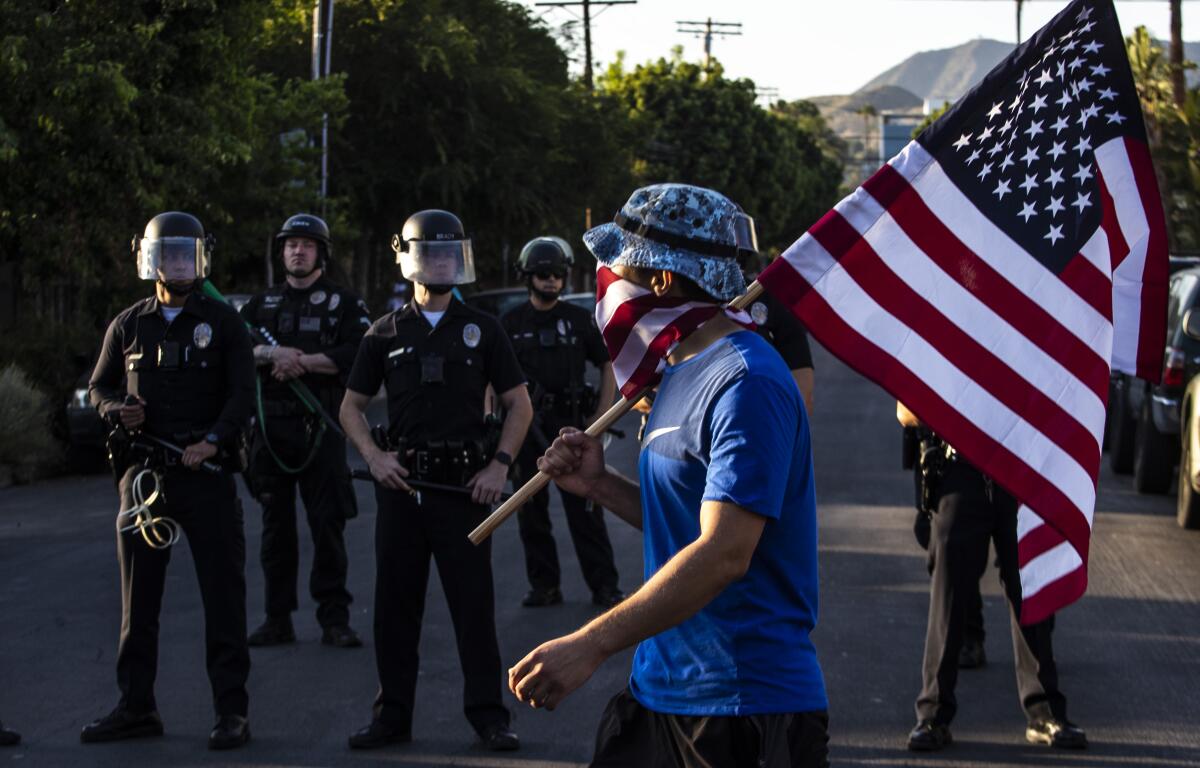 A protester carries an American flag past a line of police officers in Hollywood.