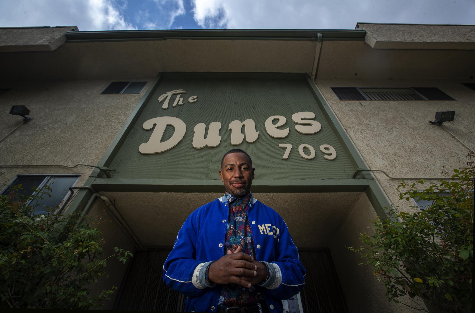 A man stands in front of a sign that says the Dunes.
