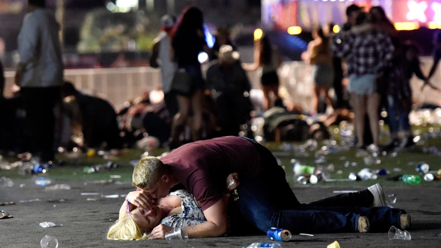 A man lays on top of a woman as others flee the Route 91 Harvest country music festival grounds after a active shooter was reported on Sunday in Las Vegas.