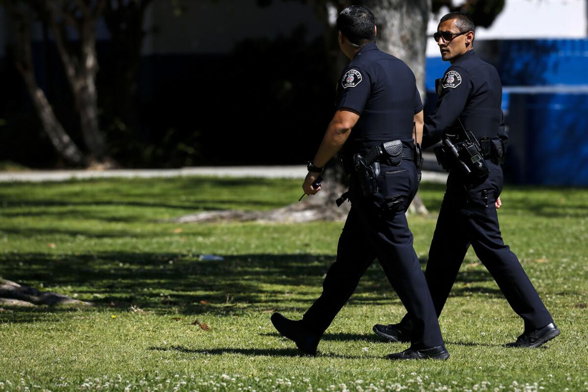 Police walk outside Venice High School Friday after officers swept into the school to arrest students suspected of pressuring two female classmates into having sex.