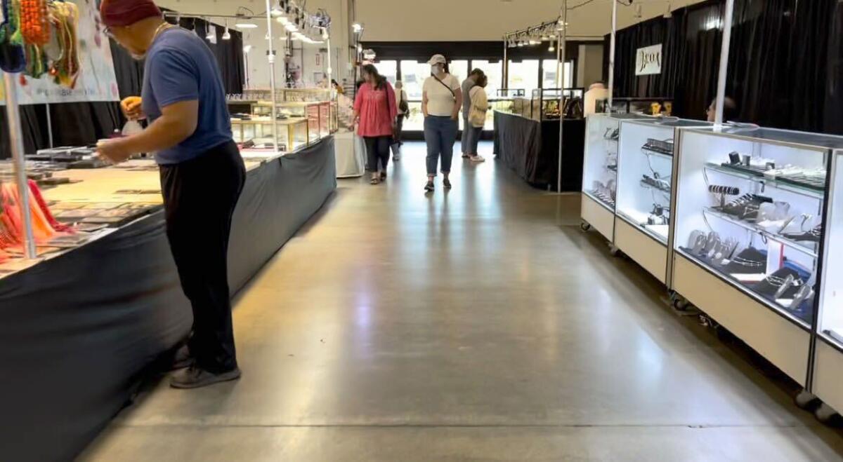 People walk between and browse two rows of jewelry displays.