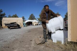 MOUNT SHASTA VISTA, CA - October 12 2021: Hmong retiree Bee Xiong stacks newly purchased portable water tanks at his 40-acre ranch the Mount Shasta Vista subdivision in Siskiyou County on Tuesday, Oct. 12, 2021 in Mount Shasta Vista, CA. Xiong will used the smaller tanks to transport water under the 100 gallon limit for delivering water to the subdivision. (Brian van der Brug / Los Angeles Times)