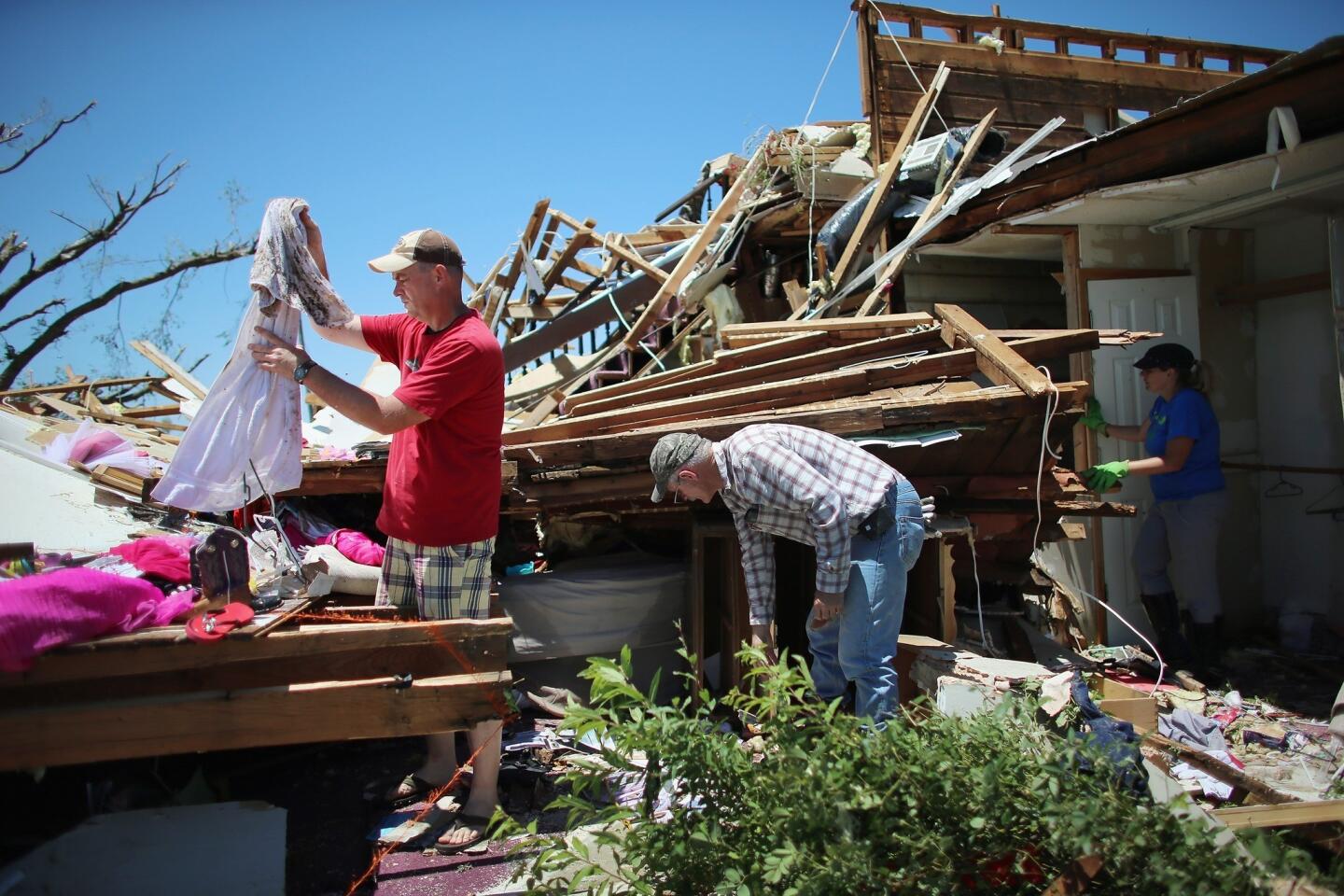 William Miles, left, Larry Corr and Kim van Aken salvage items from a home destroyed when a tornado hit Saturday in El Reno, Okla.
