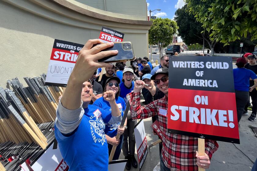 Los Angeles, CA - May 02: WGA members take a selfie before heading to the picket line on the first day of their strike in front of Paramount Studios in Hollywood on May 2, 2023. The union were unable to reach a last minute-accord with the major studios on a new three-year contract to replace one that expired Monday night. (Genaro Molina / Los Angeles Times)