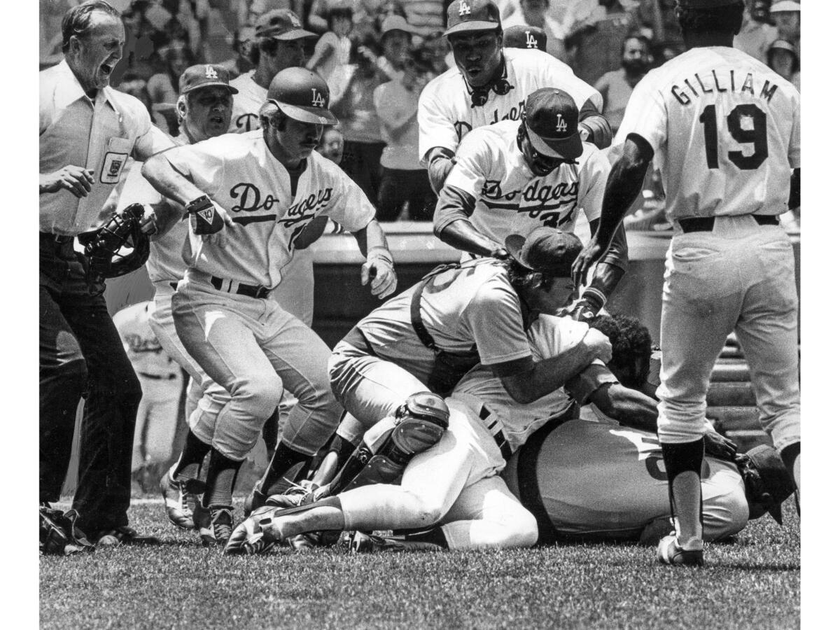 July 19, 1977: Chicago Cubs catcher George Mitterwald is on the ground grabbing Dodger Reggie Smith, who is on top of Cubs pitcher Rick Reuschel. Umpire Ed Sudol is at left.