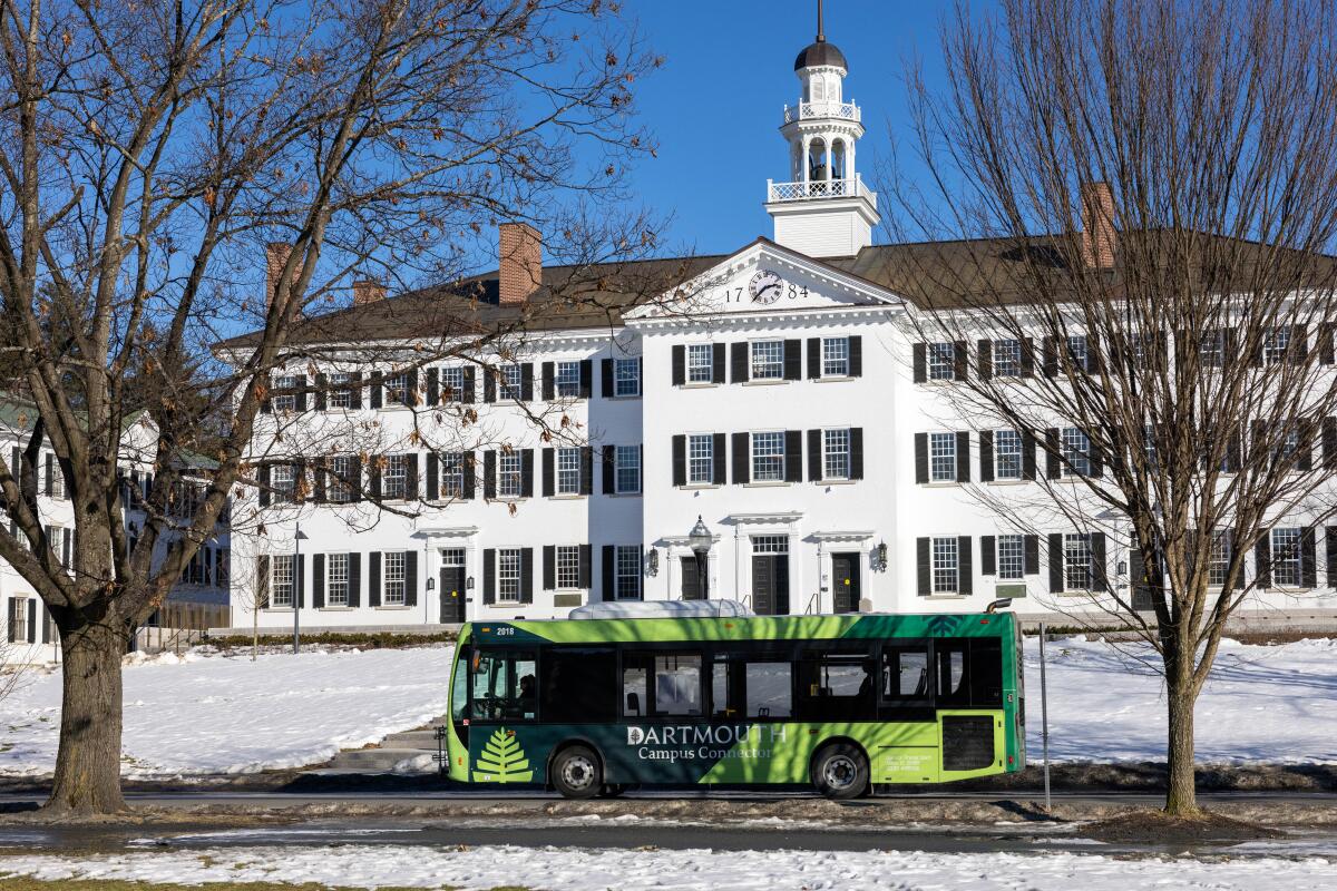 Bus drives by snowy grounds and old-style college building