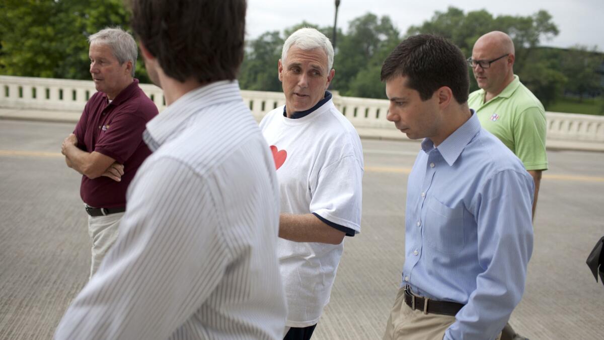 Then-Indiana Gov. Mike Pence, center, talks with South Bend Mayor Pete Buttigieg at an event in downtown South Bend in 2013.