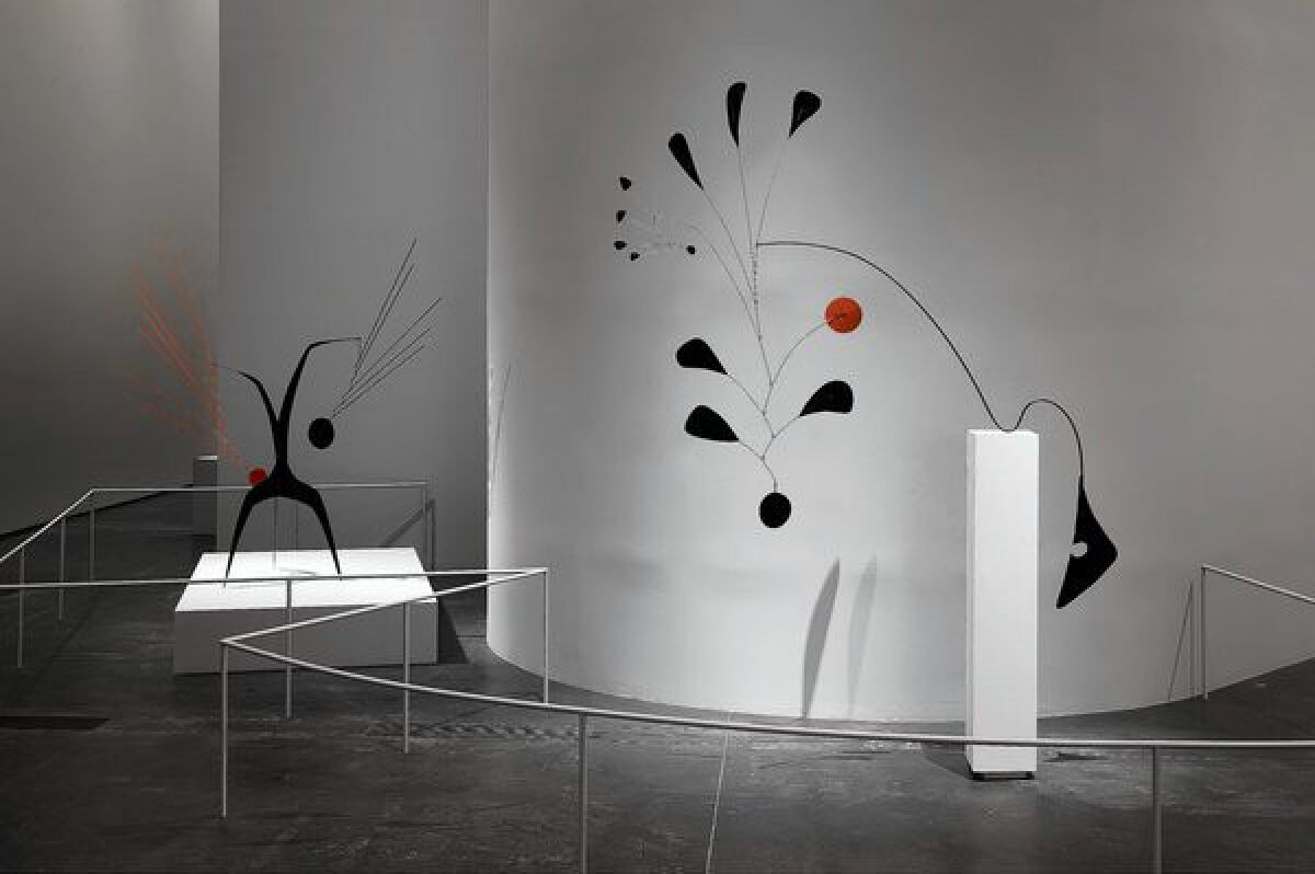 Abstract red and black metal sculptures in a museum in front of white walls