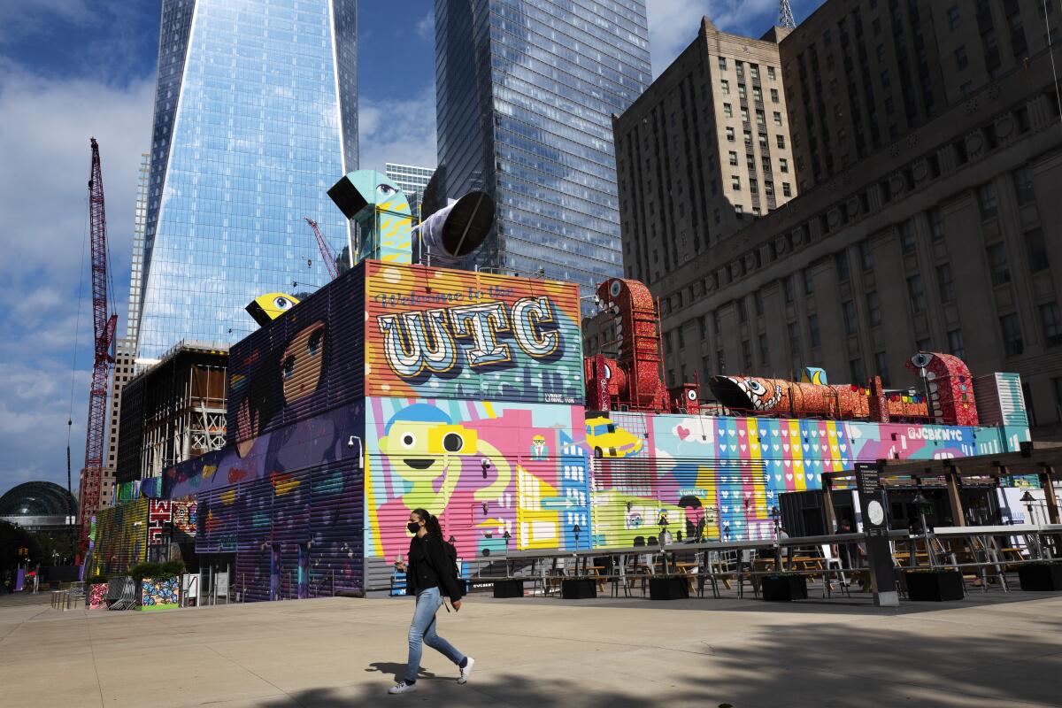 A woman walks by the colorful murals that surround the foundation for 2 World Trade Center, Wednesday, Sept. 8, 2021 in New York. Planned as the second tallest skyscraper at the site, 2 World Trade Center, might someday reach 80 stories. Developer Larry Silverstein has said he wants to sign an anchor tenant for the tower before starting construction. (AP Photo/Mark Lennihan)