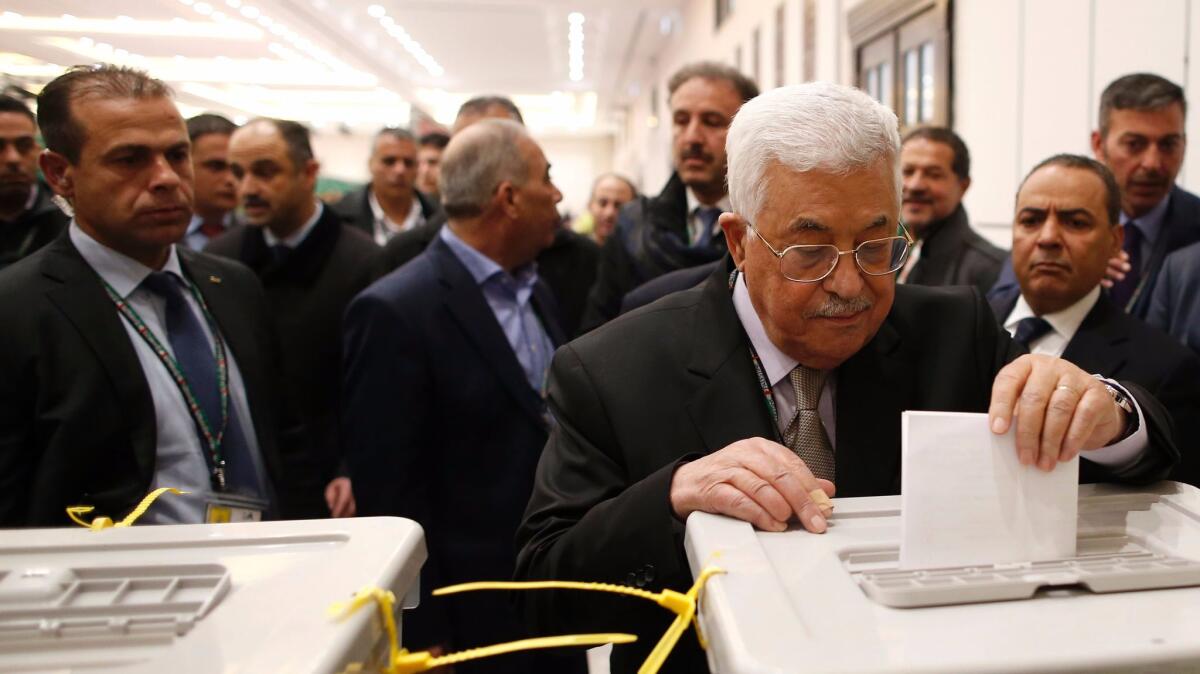 Palestinian Authority President Mahmoud Abbas, right, casts his vote at the Muqata, the authority's headquarters, in the West Bank city of Ramallah on Dec. 3, 2016.